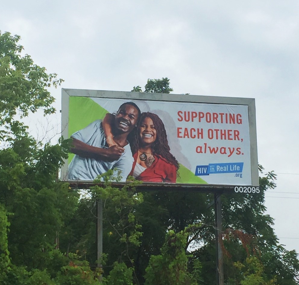 A photograph of a billboard along the road about the HIV campaign.