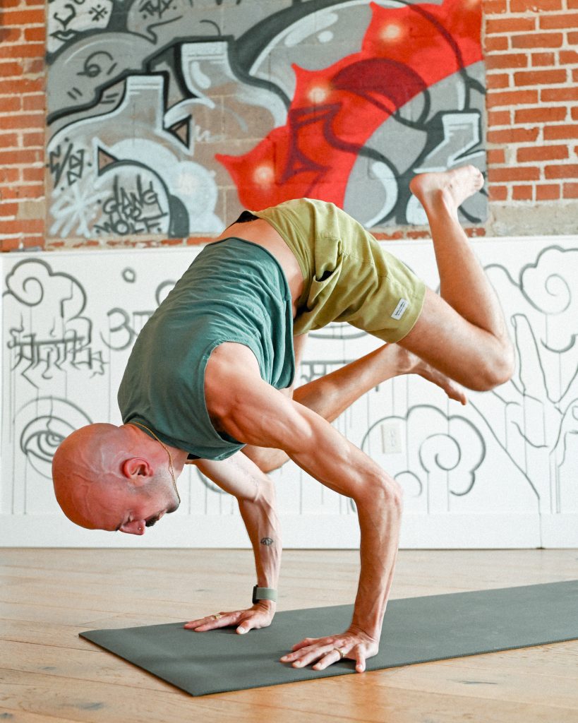 image of Nate Apuna, One Down Dog yoga teacher doing an arm balance yoga posture